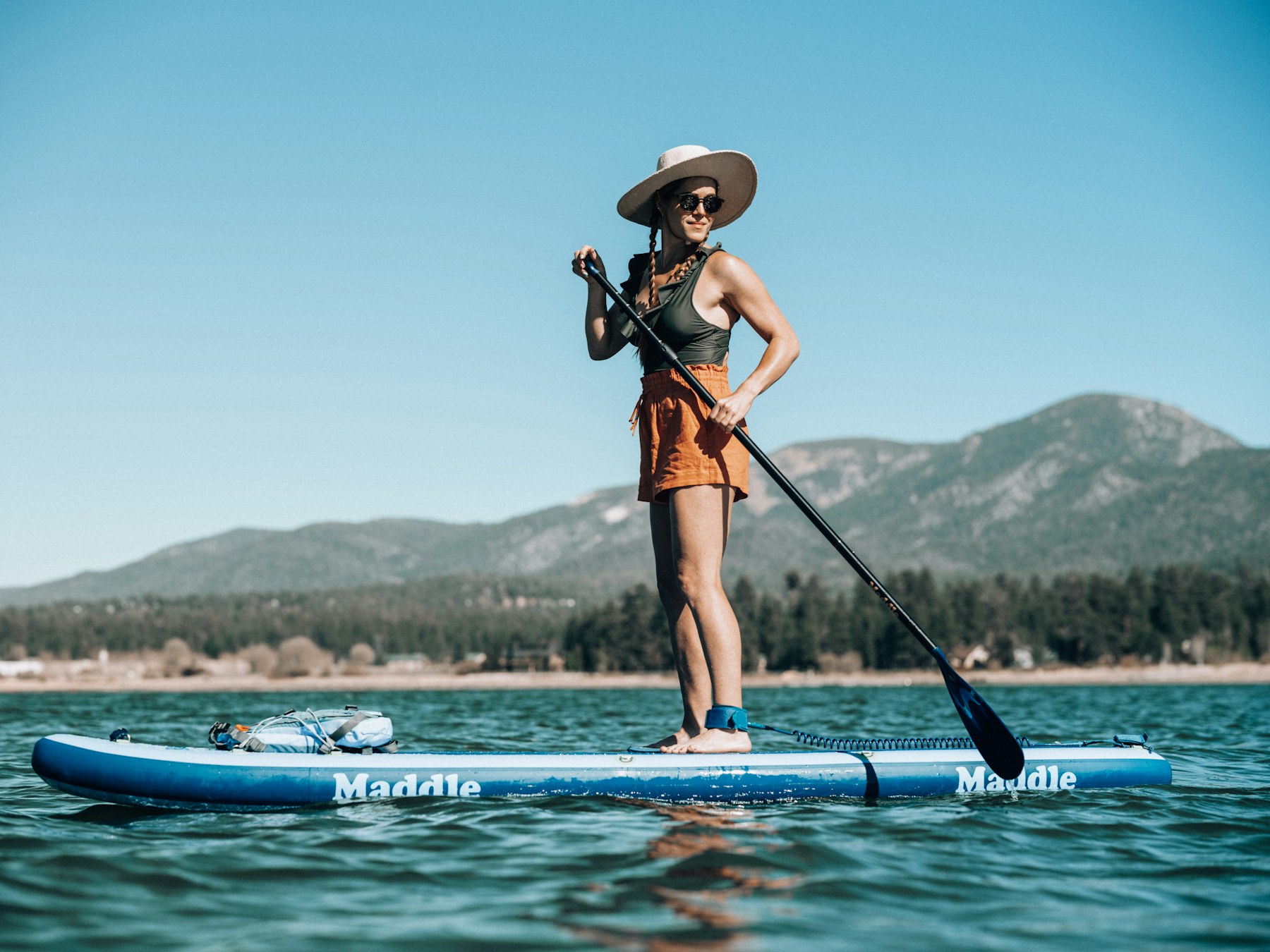 ผู้เล่นยืนพาย SUP board บนผิวน้ำ